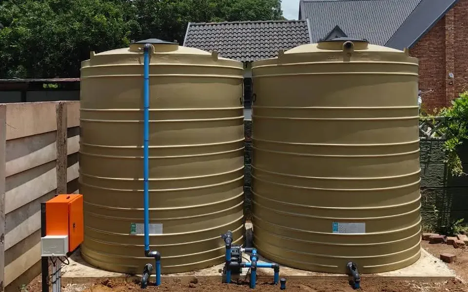 Two water storage tanks on a slab with booster pump and control box